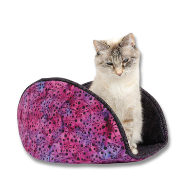 The jumbo-size Cat Canoe® modern cat bed, in a purple and pink cotton batik fabric, and lined with a black fabric with a maze design in purples and pinks. This bed was designed for larger cats, but the model here only weighs 7 pounds. Our cat beds are made in the USA.