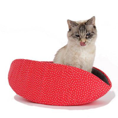 A small cat sits inside a Cat Canoe® modern cat bed. This pet bed is long and narrow with high sides that tend to form closely around your sleeping pet, helping to retain body heat.