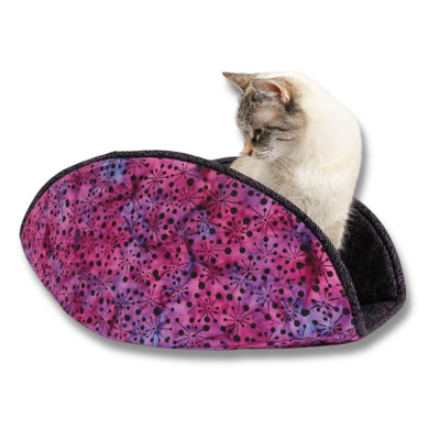 The jumbo-size Cat Canoe® modern cat bed, in a purple and pink cotton batik fabric, and lined with a black fabric with a maze design in purples and pinks. This bed was designed for larger cats, but the model here only weighs 7 pounds. Our cat beds are made in the USA.