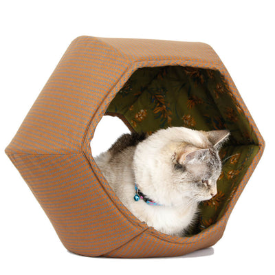 The Cat Ball® cat bed is a hexagonal cat bed with two openings, made here in brown fabric with little blue squares. The lining is a floral on a green background. This is a view from the larger opening.