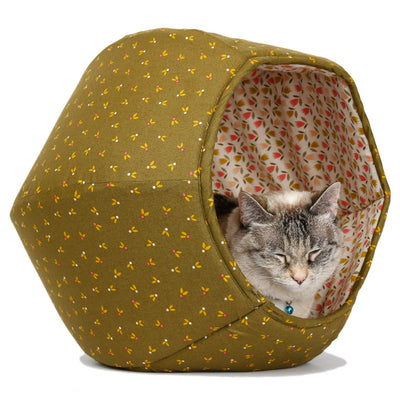 A small cat resting inside the Cat Ball kitty bed, made here in an olive green cotton with little flower buds. The lining is tulips on a white background. This floral fabric cat bed is made in the USA.